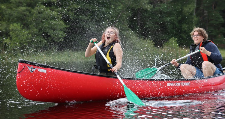 kille och tjej som paddlar i en röd kanot